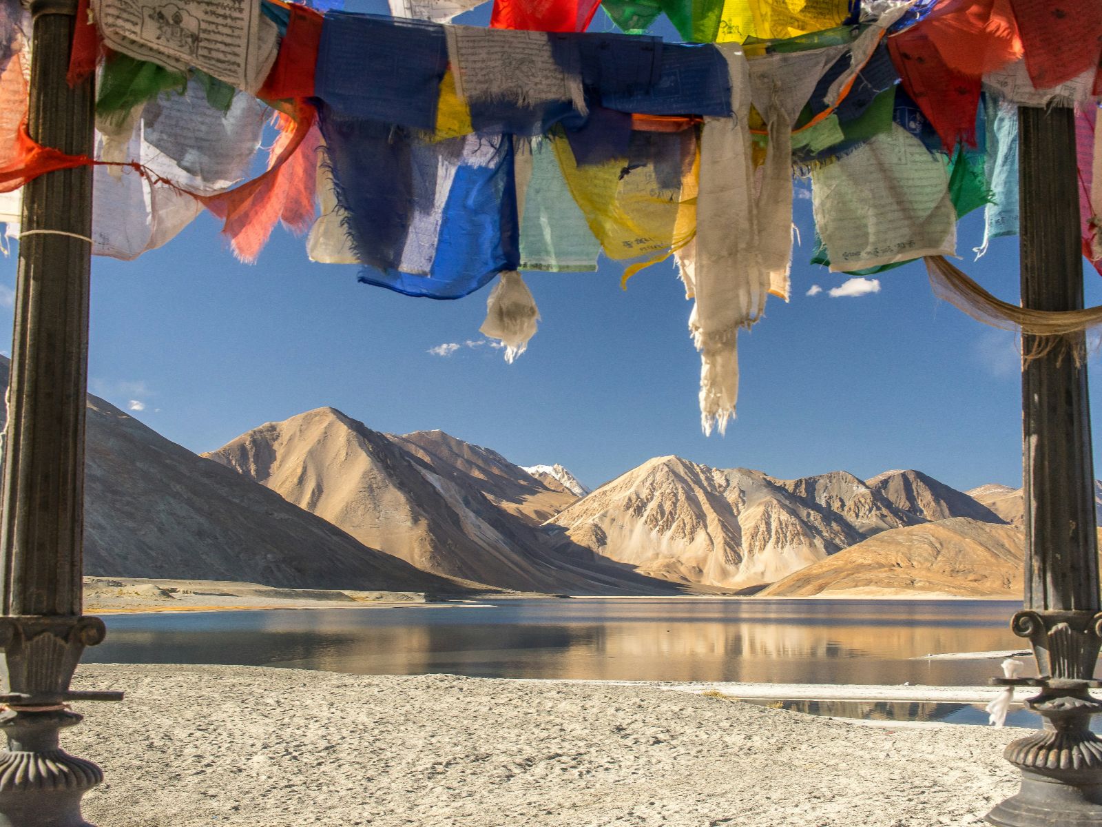 Rondreis India, Ladakh, Gebedsvlaggen aan oever van meer met bergen